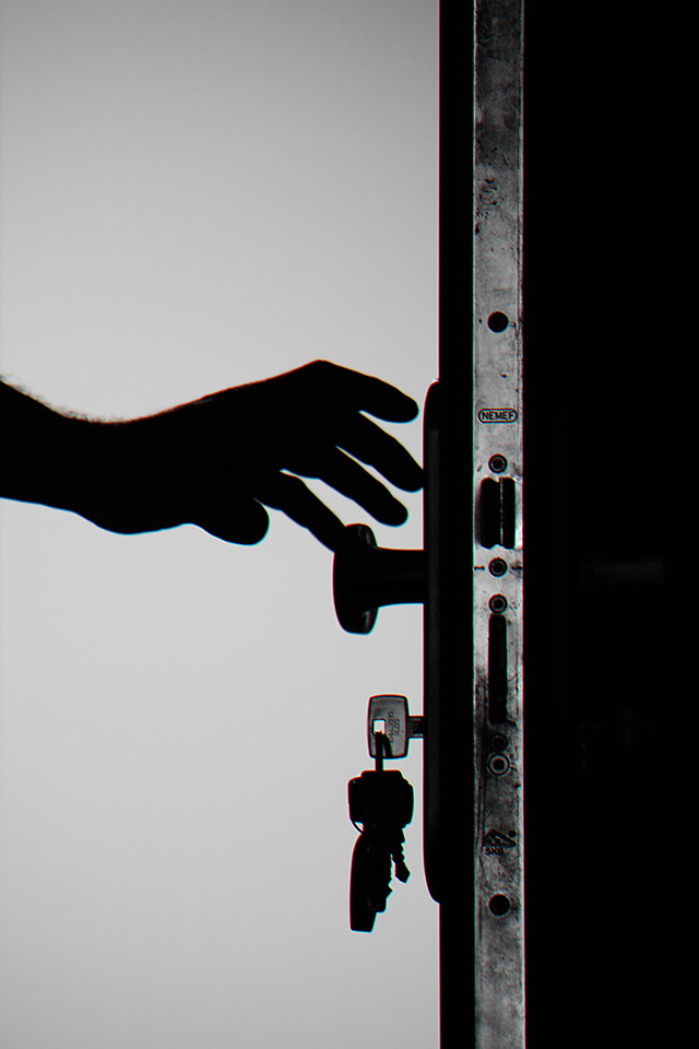 Hand unlocking a door with keys and opening it